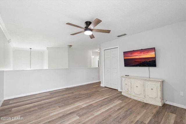 unfurnished living room with a ceiling fan, baseboards, visible vents, and wood finished floors