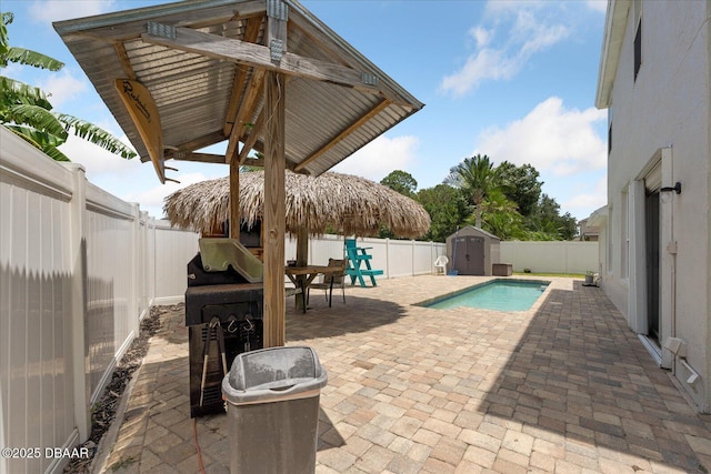 view of pool with a patio, a fenced backyard, an outbuilding, and a storage shed