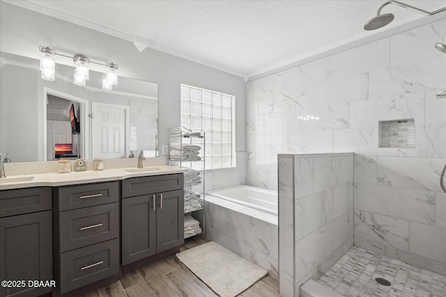 bathroom featuring crown molding, a sink, a bath, and a tile shower