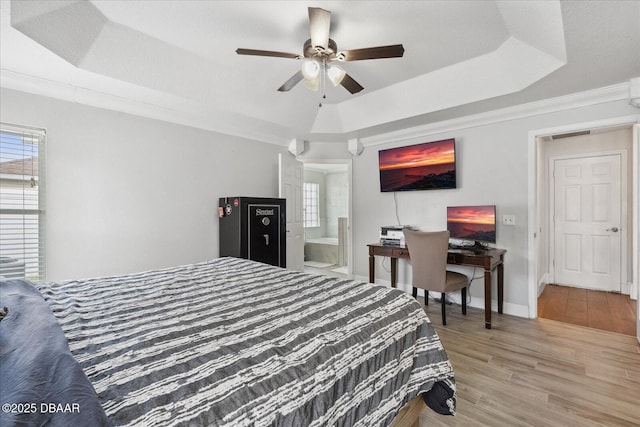 bedroom with baseboards, multiple windows, a tray ceiling, and light wood-style flooring