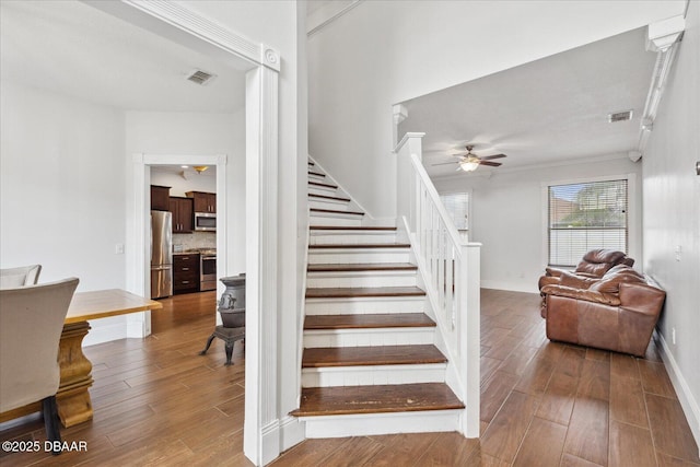 staircase with ceiling fan, wood finished floors, and visible vents