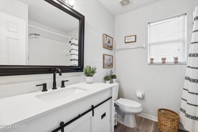 bathroom featuring vanity, toilet, baseboards, wood finished floors, and visible vents