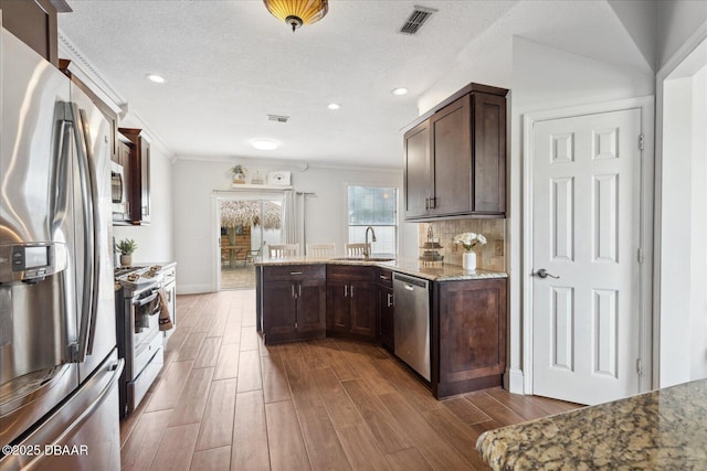 kitchen with visible vents, ornamental molding, dark wood-type flooring, a sink, and appliances with stainless steel finishes