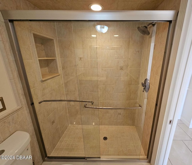 bathroom with tile patterned flooring, toilet, and an enclosed shower