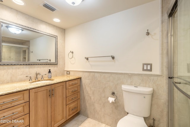 bathroom featuring vanity, tile patterned flooring, toilet, tile walls, and walk in shower