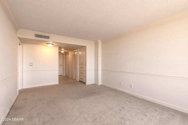 carpeted empty room featuring ornamental molding and a textured ceiling