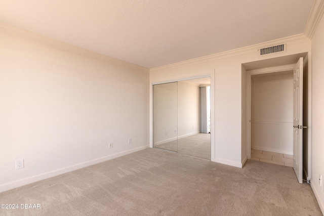 unfurnished bedroom featuring light colored carpet, a closet, and crown molding