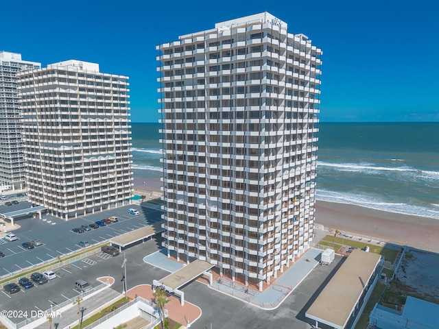 view of building exterior featuring a water view and a beach view