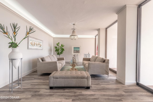 living room featuring wood-type flooring, a textured ceiling, and ornamental molding