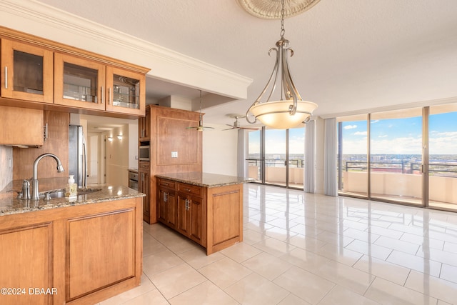 kitchen with pendant lighting, ceiling fan, light tile patterned floors, light stone countertops, and stainless steel refrigerator