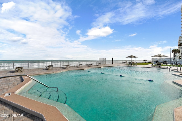 view of pool featuring a water view and a patio area