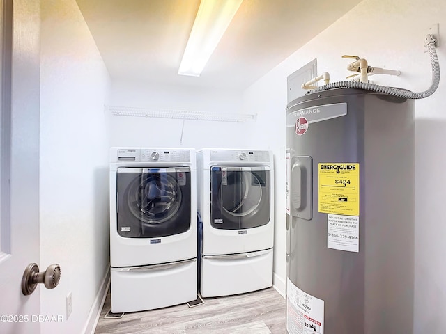 laundry room with washing machine and clothes dryer, electric water heater, and light hardwood / wood-style flooring