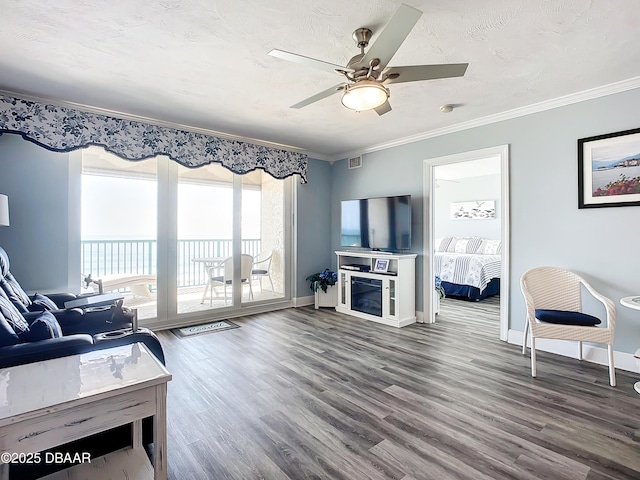 living room with hardwood / wood-style flooring, ornamental molding, ceiling fan, and a textured ceiling