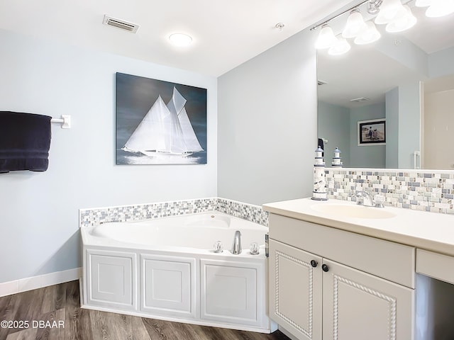 bathroom featuring hardwood / wood-style flooring, vanity, a bath, and backsplash