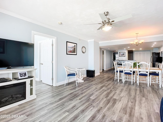 living room featuring crown molding, ceiling fan with notable chandelier, and light hardwood / wood-style floors