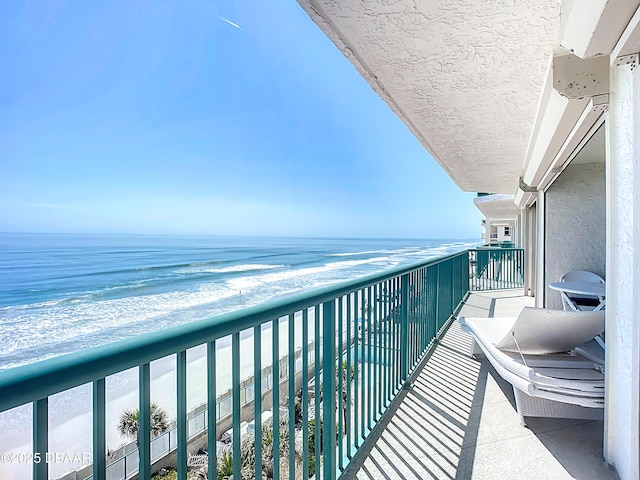 balcony with a water view and a view of the beach