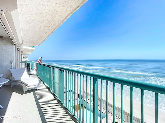 balcony featuring a water view and a view of the beach