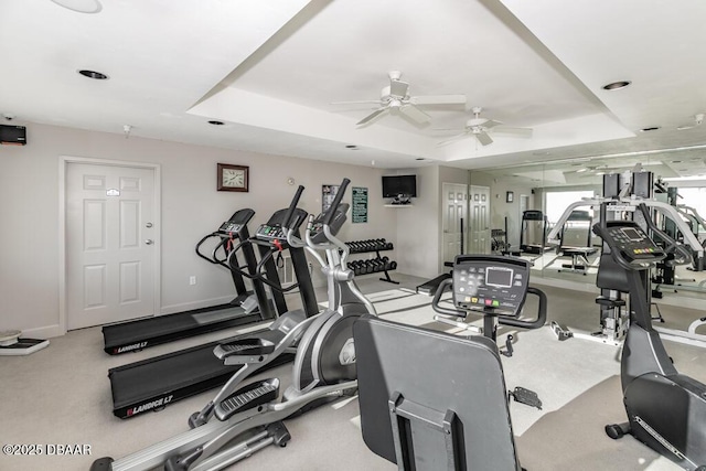 exercise room with ceiling fan and a tray ceiling