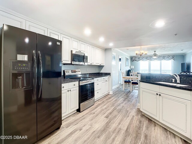 kitchen featuring white cabinetry, light hardwood / wood-style flooring, stainless steel appliances, and dark stone counters