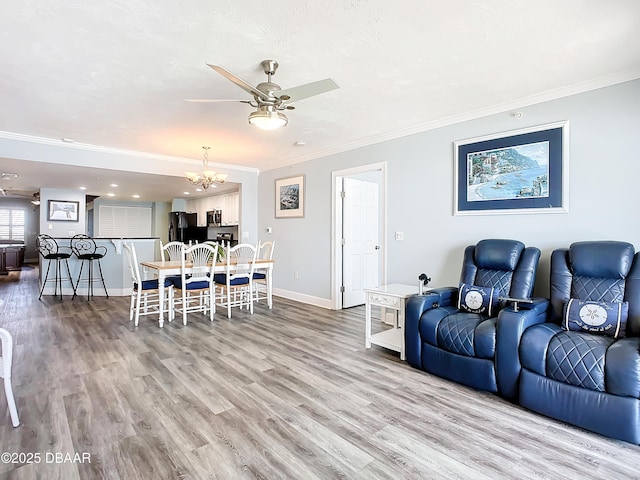 living room with crown molding, ceiling fan with notable chandelier, and light hardwood / wood-style flooring