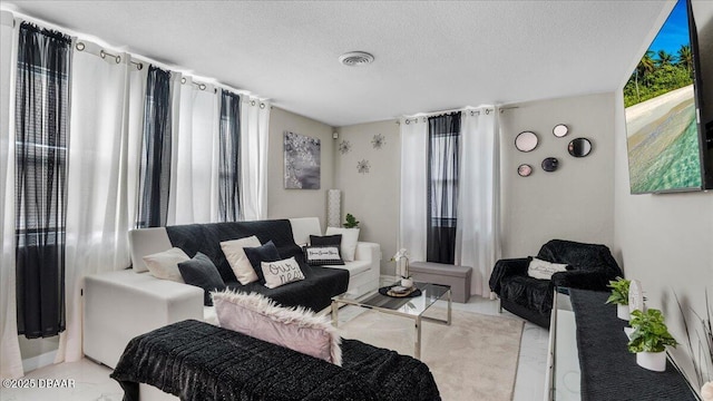 living room featuring visible vents, a textured ceiling, and a healthy amount of sunlight