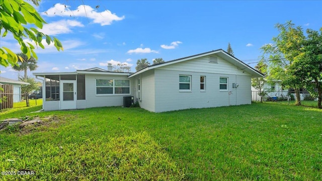 rear view of house featuring central AC, a lawn, fence, and a sunroom