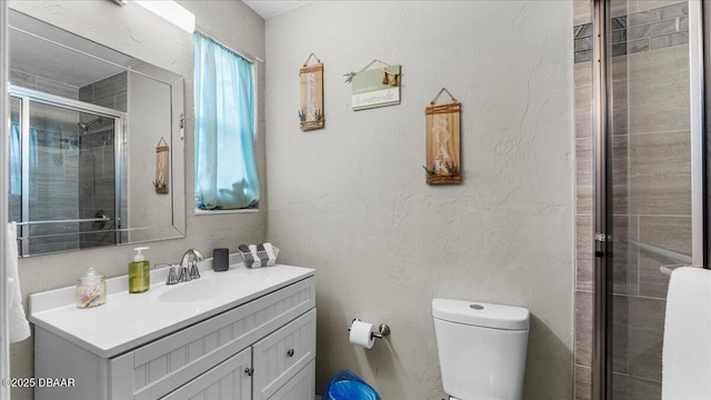 bathroom with vanity, toilet, a shower stall, and a textured wall