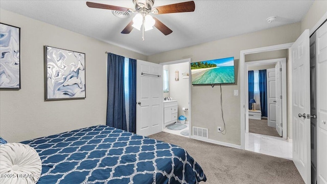 bedroom with visible vents, ceiling fan, carpet flooring, ensuite bath, and a textured ceiling