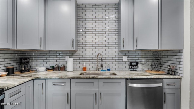 kitchen featuring stainless steel dishwasher, light stone countertops, backsplash, and a sink