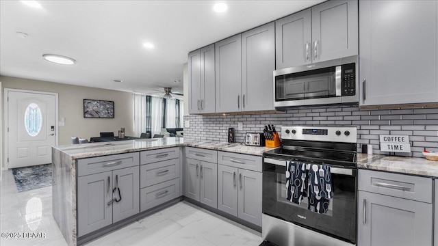 kitchen with a peninsula, gray cabinetry, marble finish floor, and stainless steel appliances