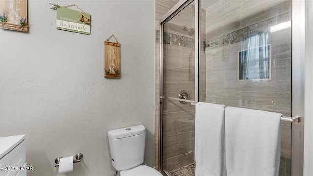 full bathroom featuring vanity, toilet, a textured wall, and a stall shower