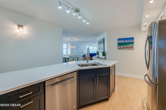 kitchen with a sink, light wood-style floors, appliances with stainless steel finishes, light countertops, and baseboards