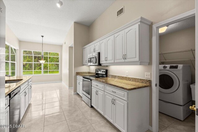 3 Slow Stream Way, Ormond Beach, FL 32174 - kitchen featuring appliances with stainless steel finishes, washer / dryer, stone countertops, light tile patterned floors, and white cabinets