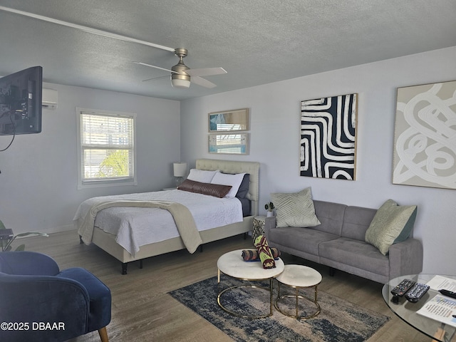 bedroom featuring ceiling fan, baseboards, wood finished floors, and a textured ceiling