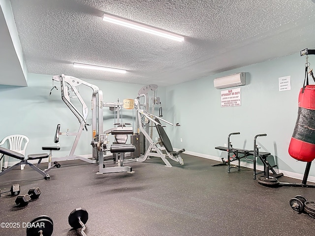 workout area featuring a wall mounted AC, a textured ceiling, and baseboards