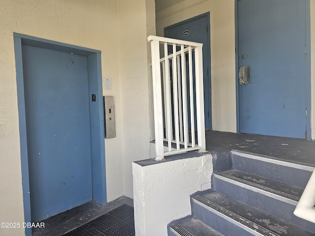 entrance to property featuring stucco siding and elevator