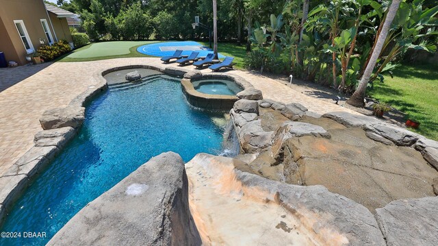 view of swimming pool with a patio area, a yard, and an in ground hot tub