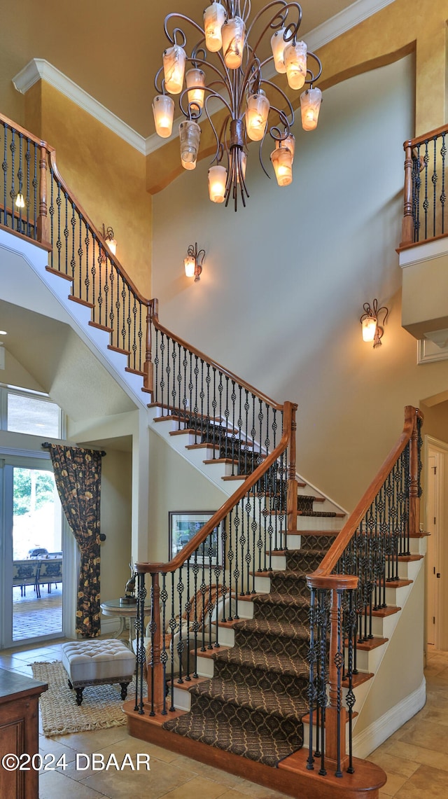 staircase with crown molding, a high ceiling, and an inviting chandelier