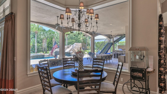 dining space with ceiling fan with notable chandelier, a textured ceiling, and ornamental molding