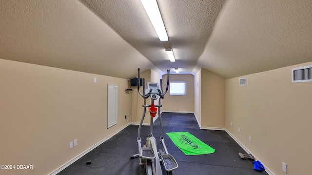 exercise room with a textured ceiling and vaulted ceiling