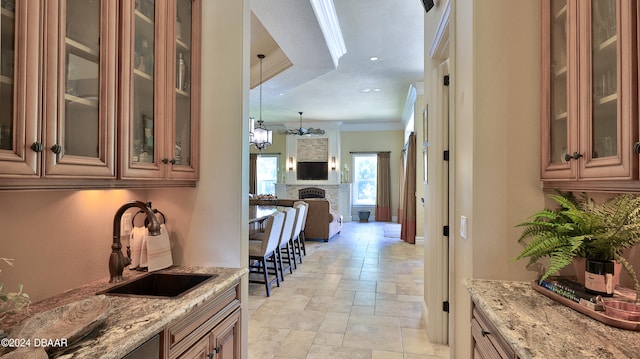 interior space with pendant lighting, light stone counters, ornamental molding, and sink