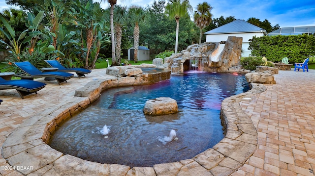 view of swimming pool featuring pool water feature, a patio, a hot tub, and a storage unit