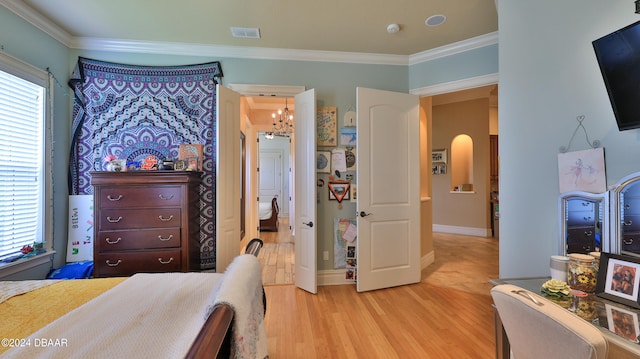 bedroom with light wood-type flooring, ornamental molding, and an inviting chandelier