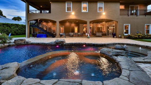 view of swimming pool with a jacuzzi, pool water feature, a shed, and a patio area