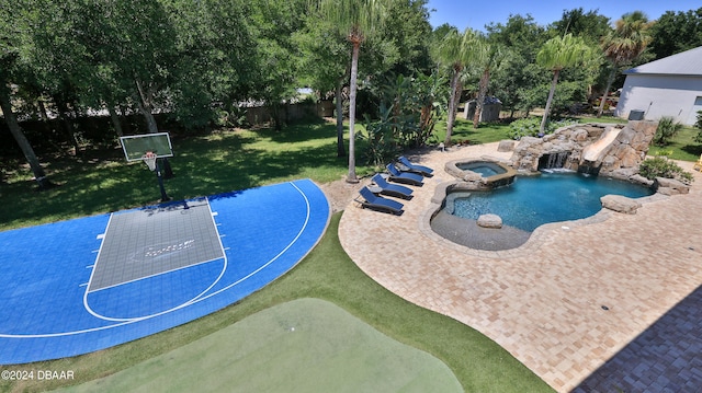 view of pool with an in ground hot tub, a yard, and basketball hoop