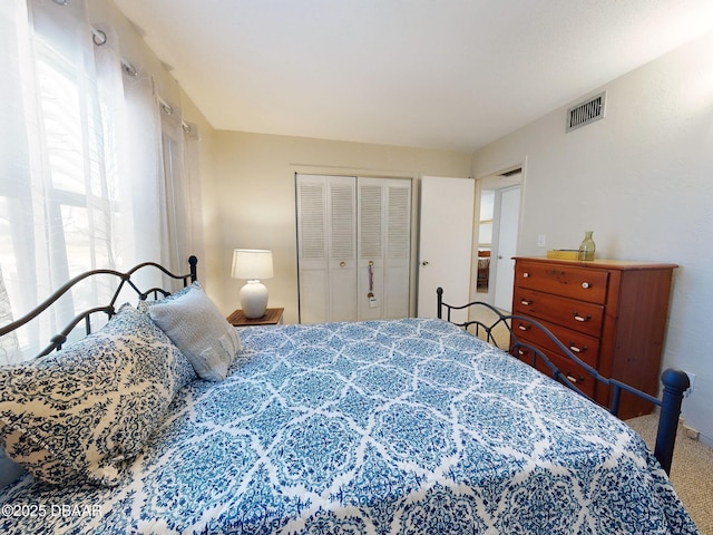 carpeted bedroom with visible vents and a closet