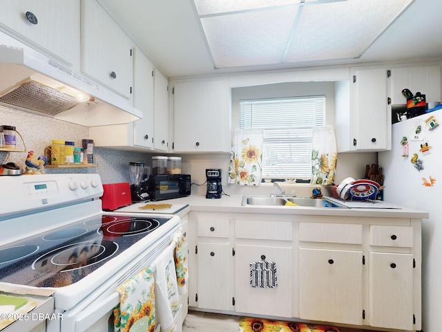kitchen featuring white appliances, light countertops, white cabinetry, under cabinet range hood, and a sink