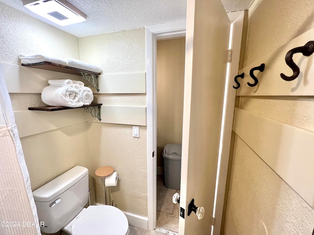 bathroom featuring toilet, a textured ceiling, and tile patterned flooring