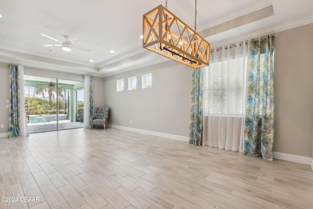 spare room featuring light wood-type flooring, ceiling fan, crown molding, and a tray ceiling