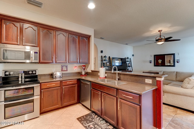 kitchen featuring kitchen peninsula, sink, light tile patterned floors, ceiling fan, and appliances with stainless steel finishes